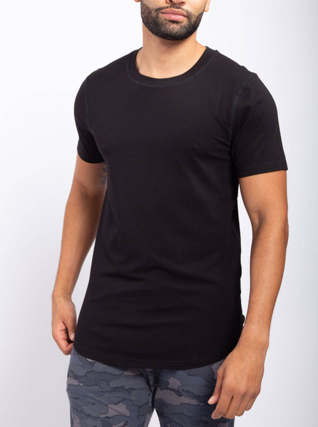 male model wearing black curved hem tee with camo pants