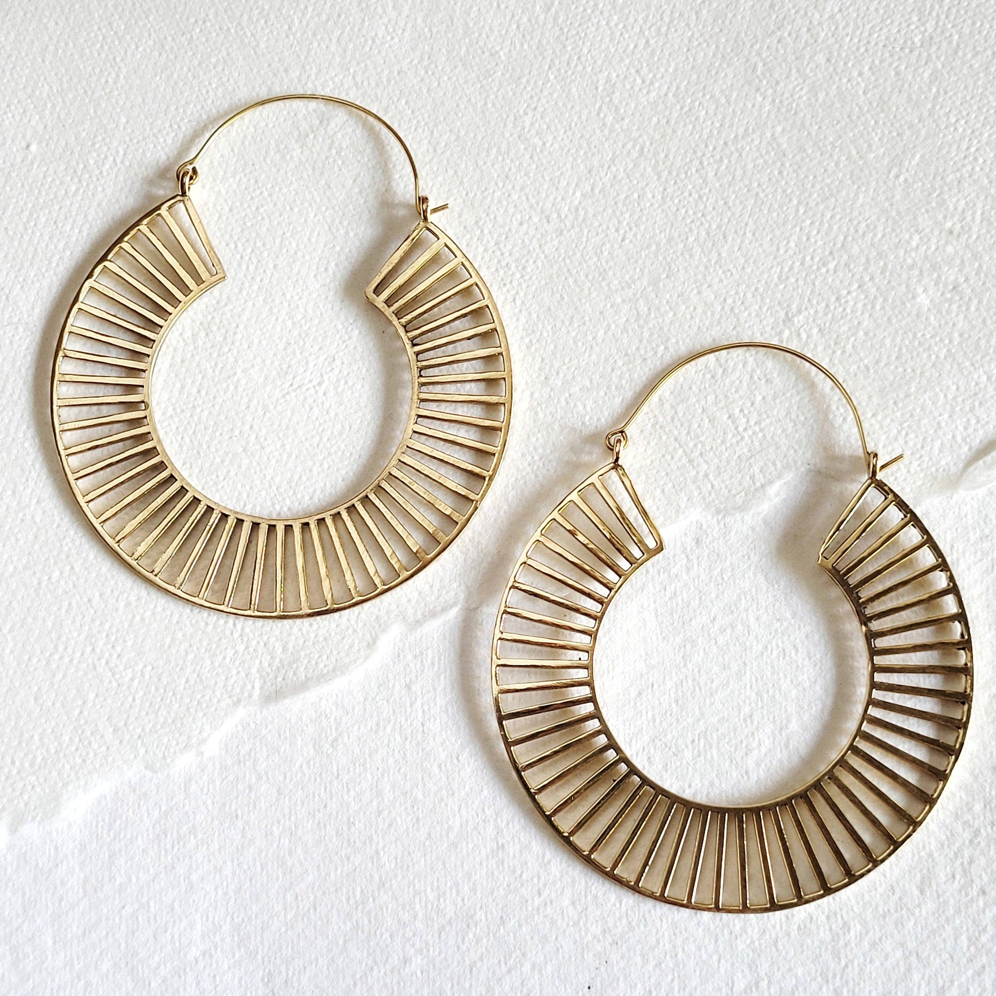 brass hoop earrings hook closure and spindle design on white background