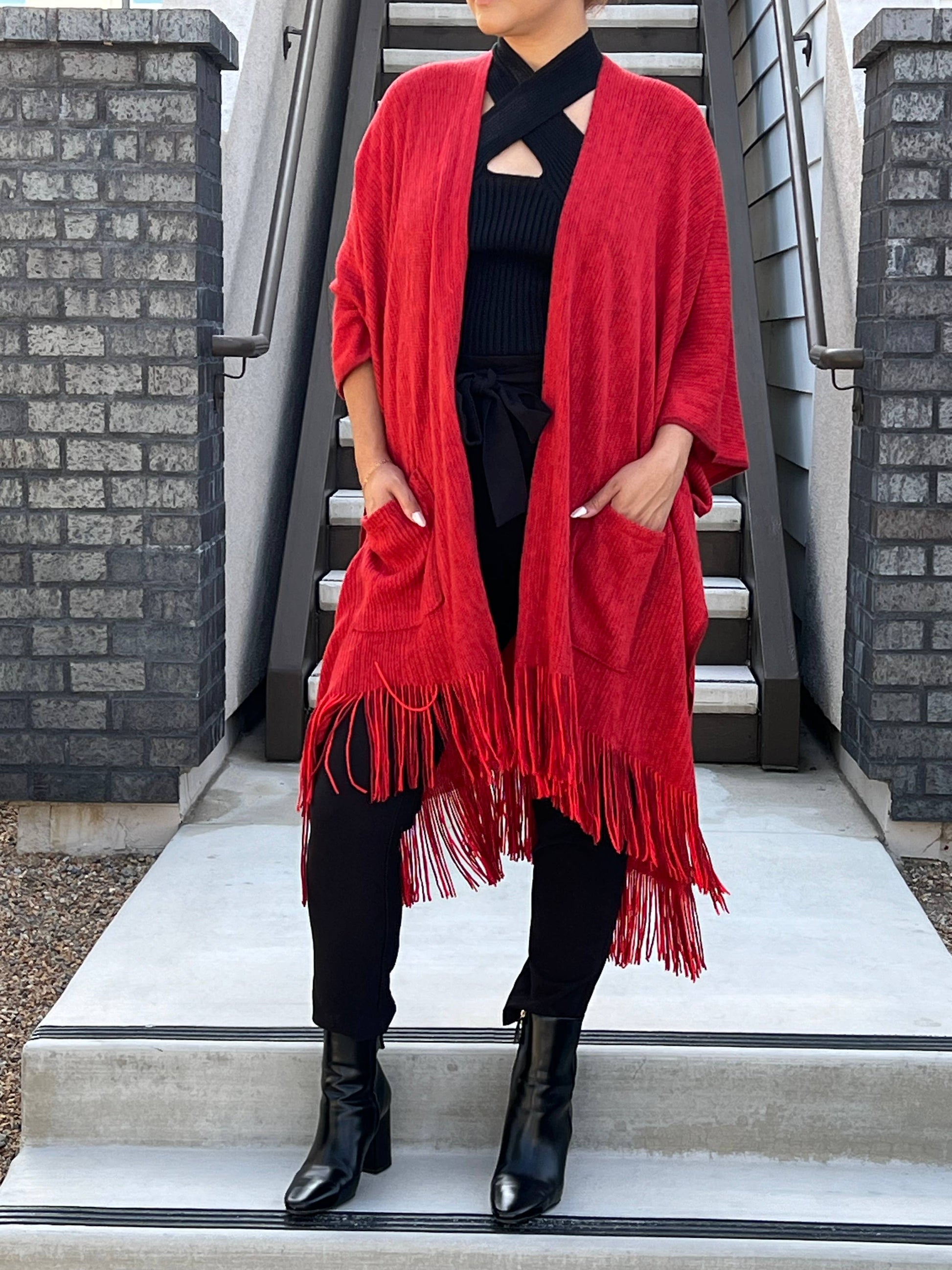 model wearing red shawl with a fringe hem, black top, pants and boots