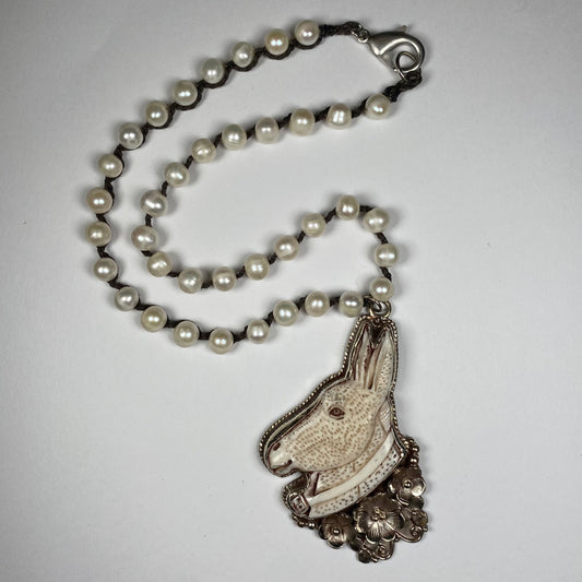 Carved  bone donkey with silver flower pendant with white pearl strand necklace.