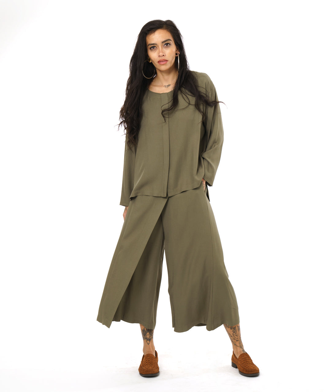 model in an olive green wide leg pant with an overlay in the front, with a matching long sleeve top with a false placket 