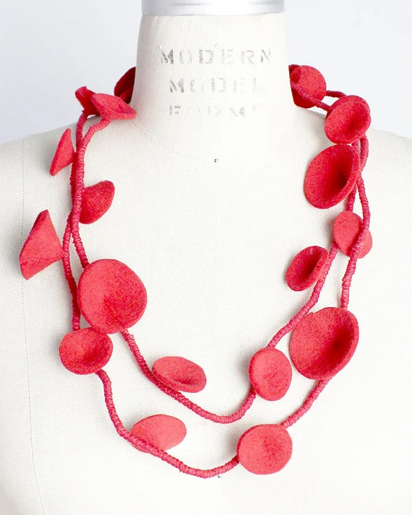 A bright red multi-strand necklace made of layered circular and petal-like pieces, displayed on a white mannequin torso.