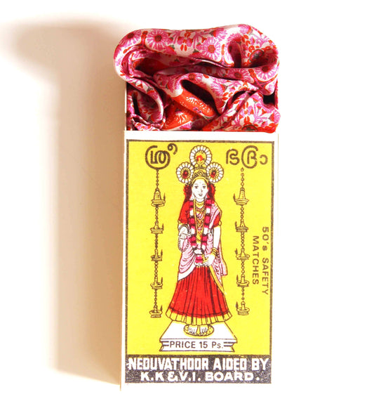 Matchbox with a colorful design featuring a woman in traditional attire on a yellow background.