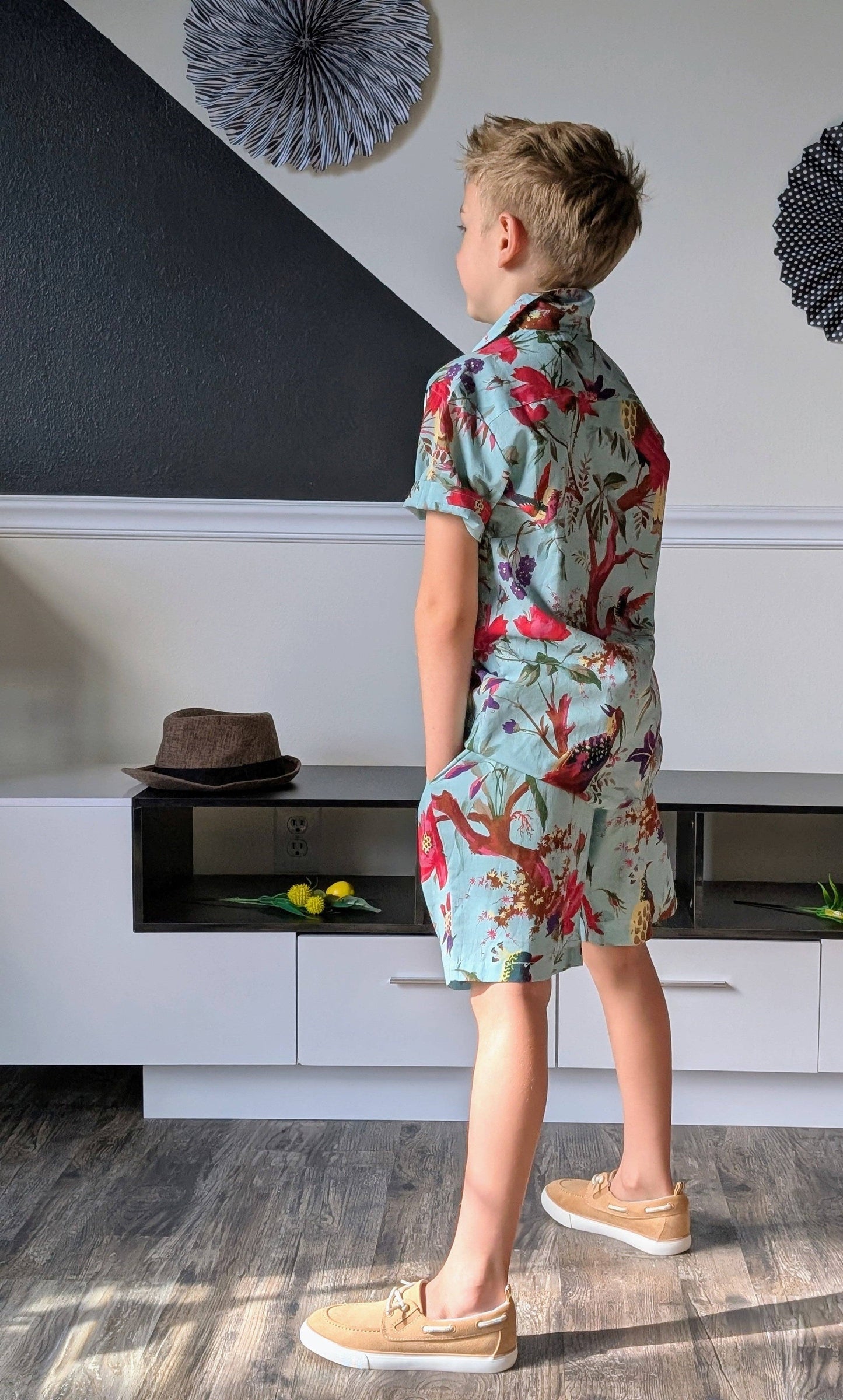 Child wearing a colorful floral outfit standing in a room with modern decor.