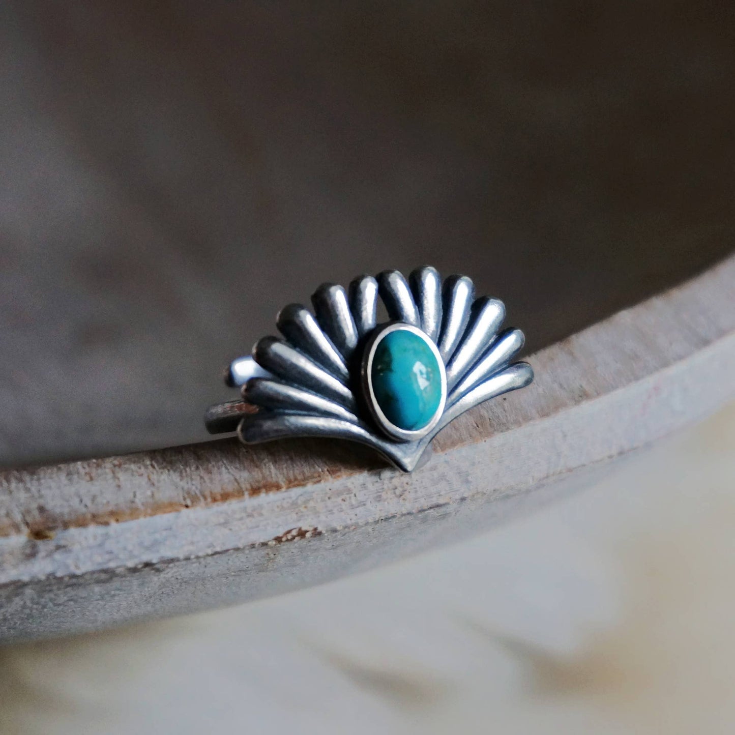 Silver ring with a turquoise stone on a wooden surface
