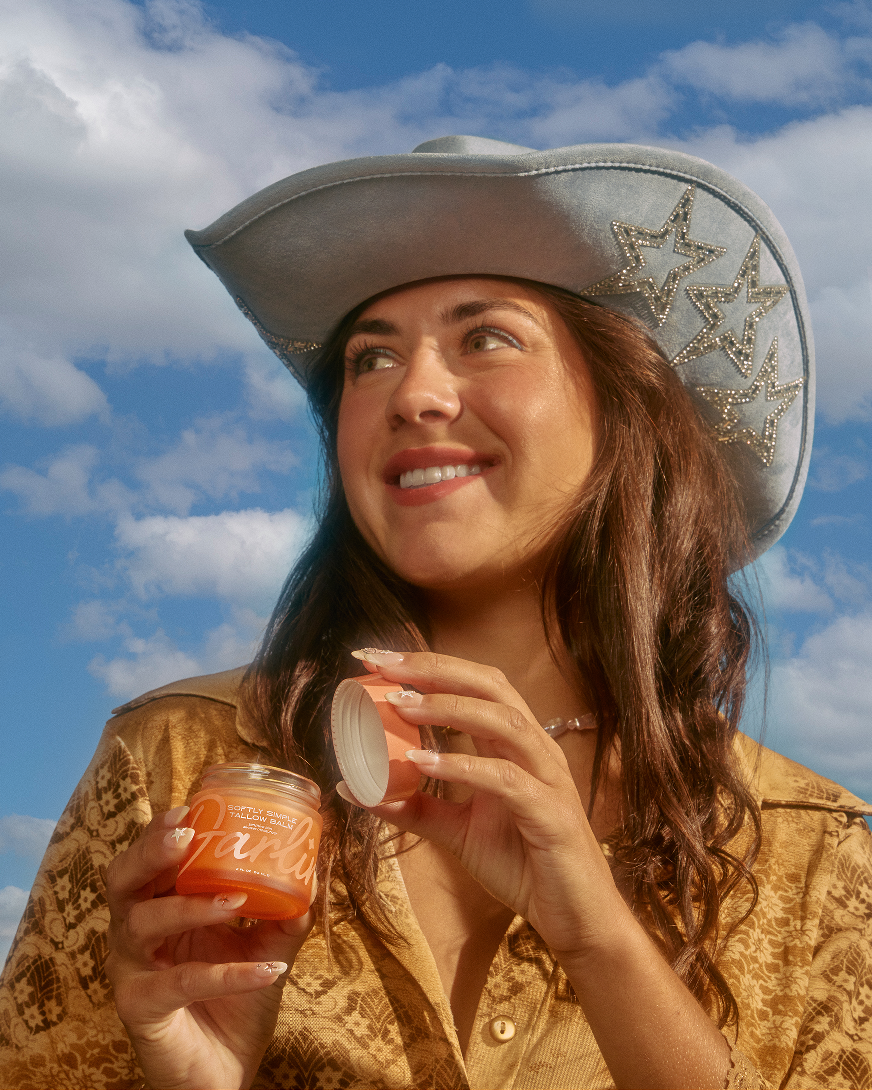 Woman in cowboy hat holding a jar with a blue sky background