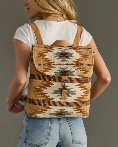 Person wearing a patterned backpack against a neutral background