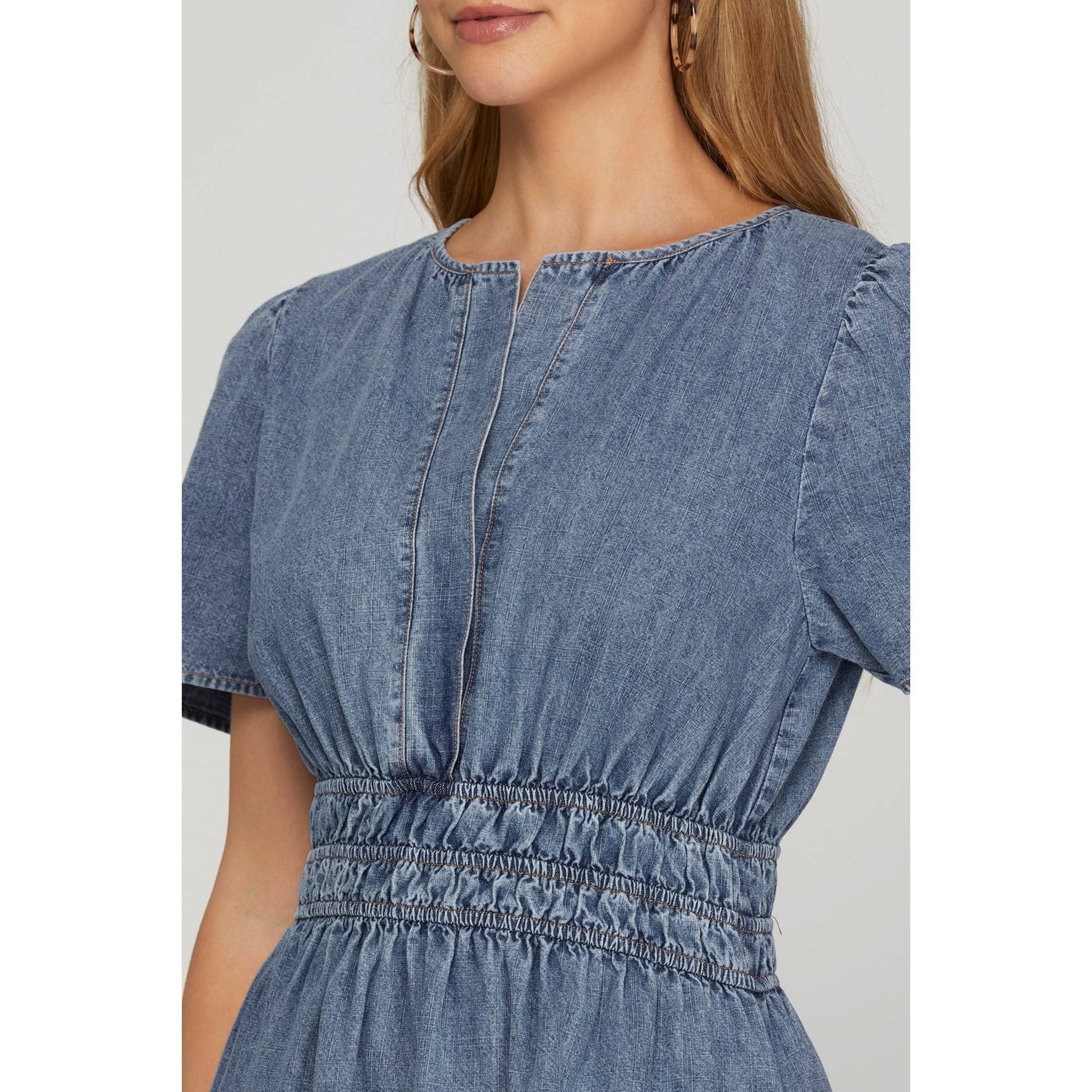 close up of woman wearing a blue washed denim short sleeve dress with elastic waistband 