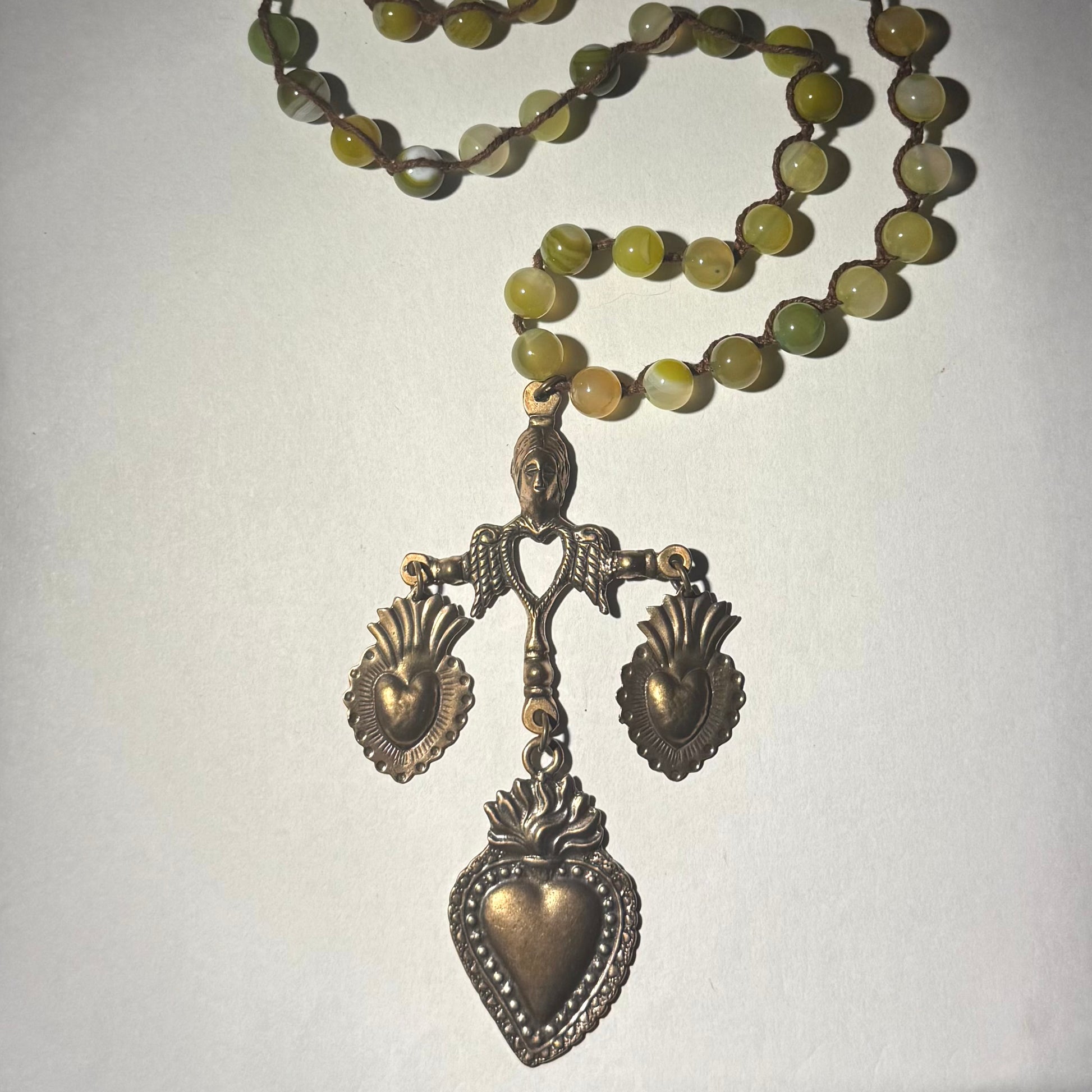 Necklace with green beads and bronze yalalag pendants on a plain background