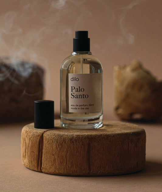 Palo Santo essential oil bottle on a wooden platform with smoke in the background