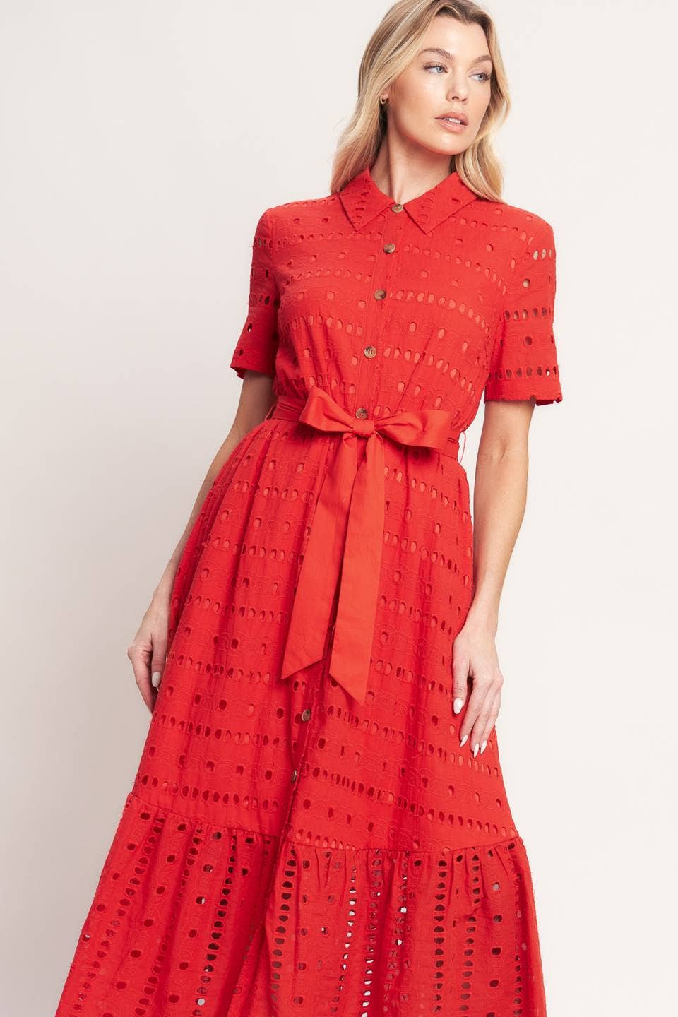 Woman wearing a red dress with a belt against a plain background