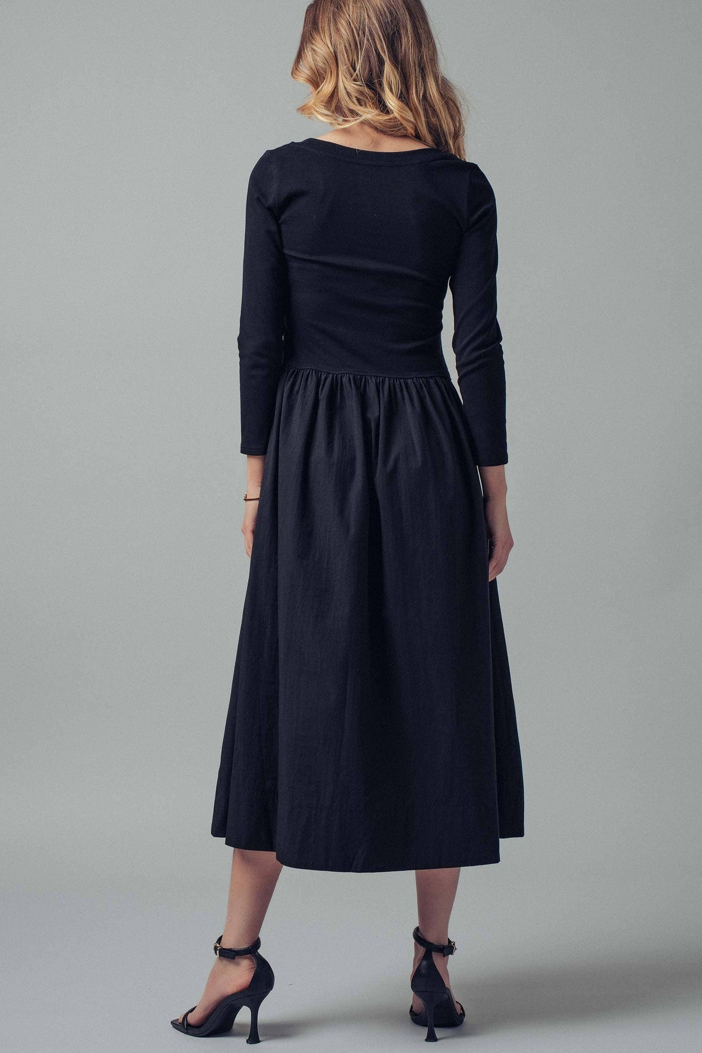 Woman wearing a black dress against a gray background