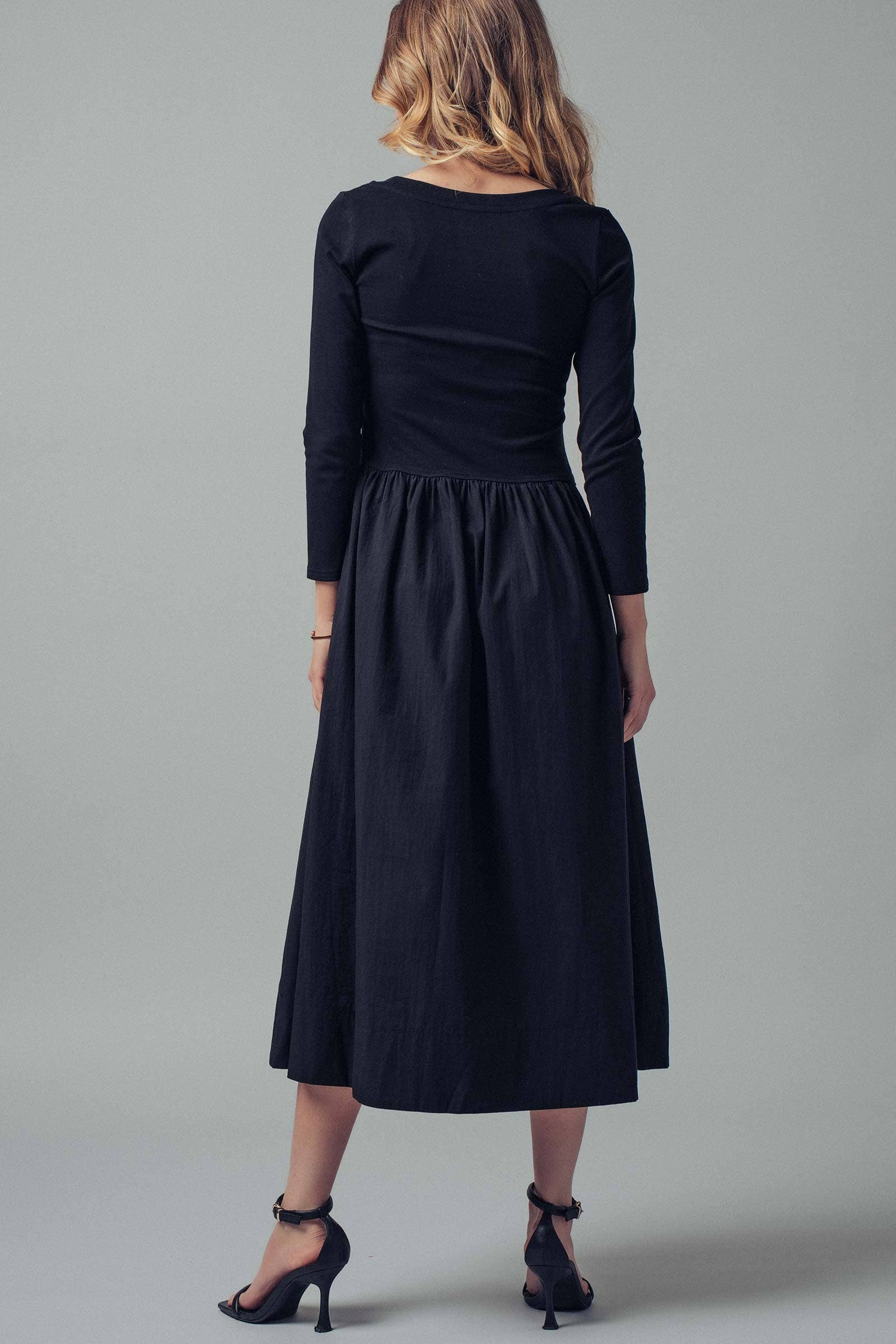 Woman wearing a black dress against a gray background