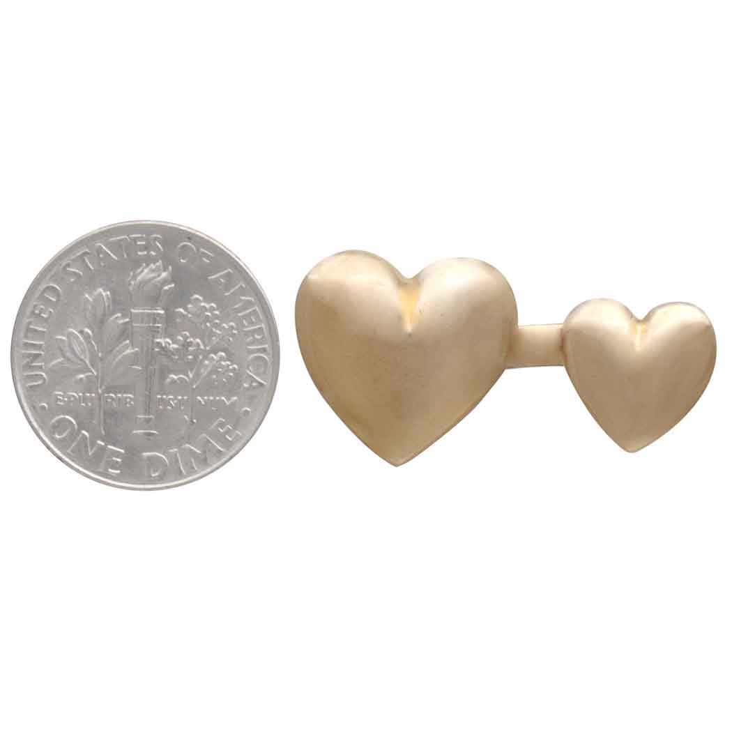 Gold heart-shaped ring next to a U.S. quarter for size comparison on a white background