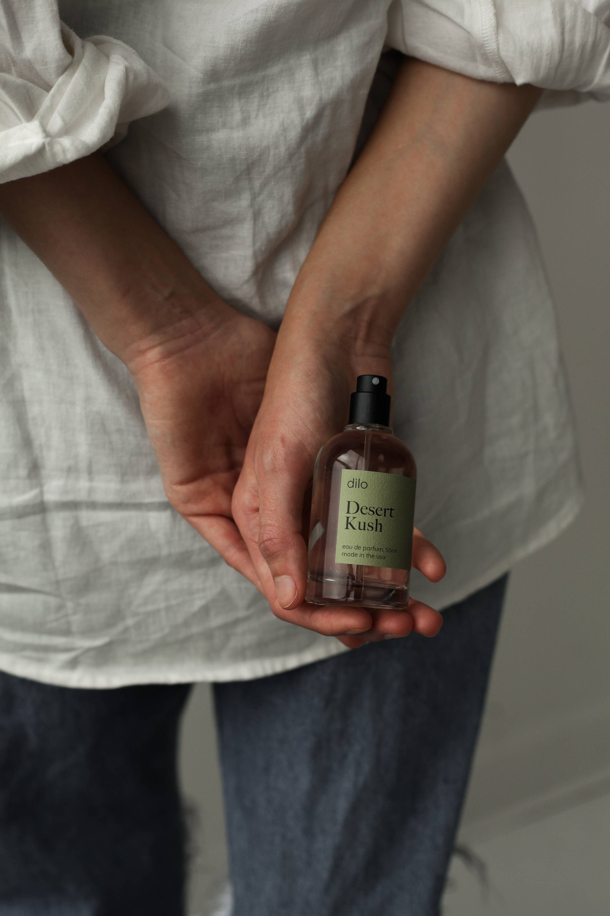 Person holding a bottle labeled 'Desert Kush' against a neutral background
