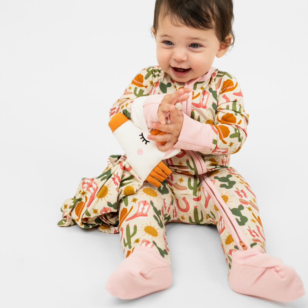 Baby wearing a colorful outfit with cactus pattern on a white background