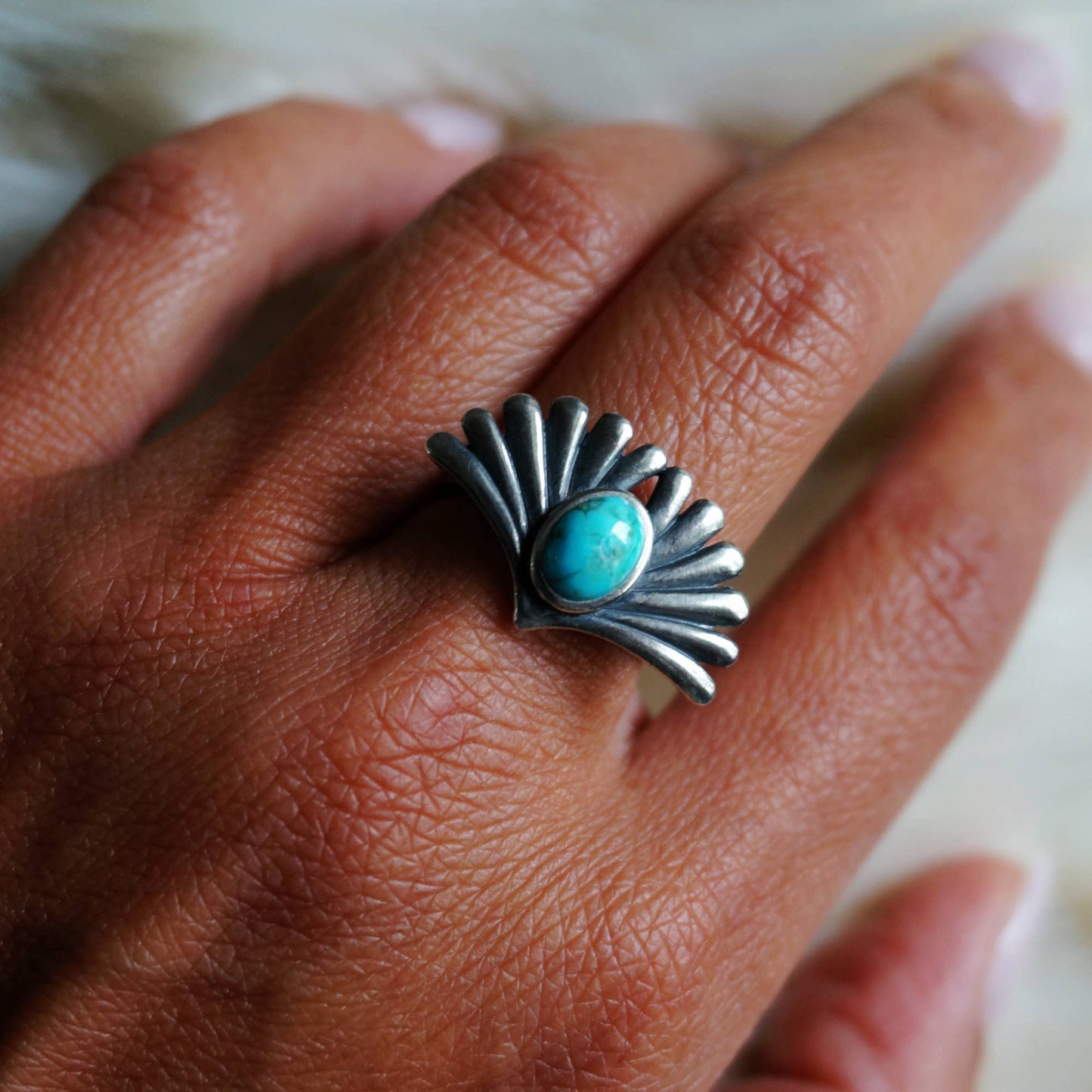 Silver ring with a turquoise stone on a person's finger