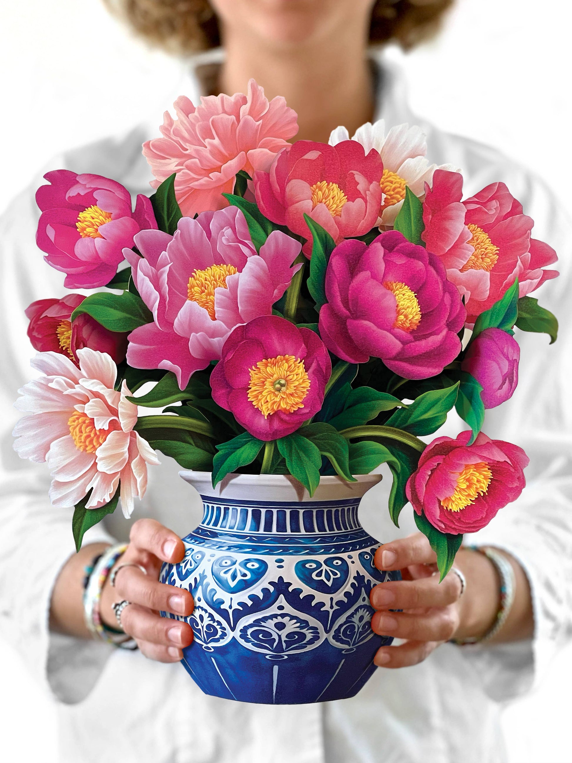 Person holding a blue and white patterned vase with pink and green flowers.
