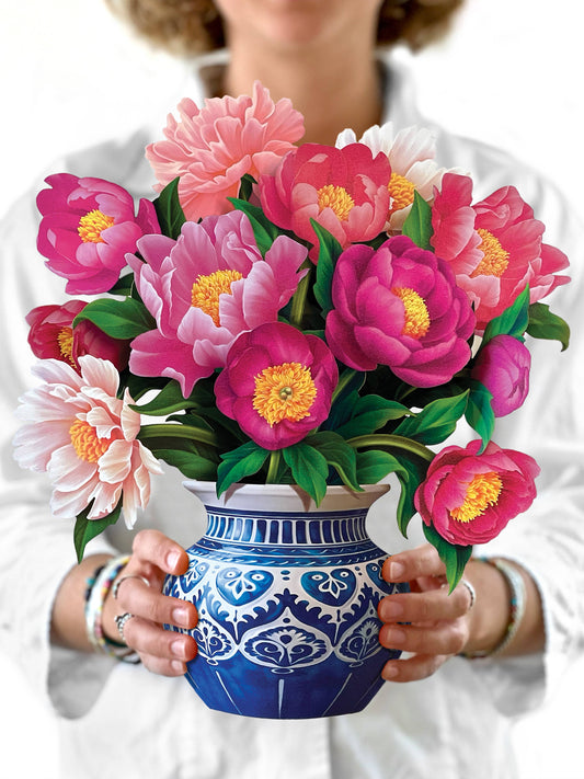Person holding a blue and white patterned vase with pink and green flowers.