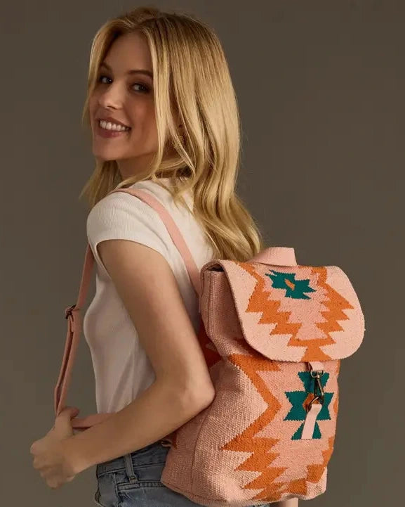 Woman carrying a pink and orange patterned backpack against a brown background