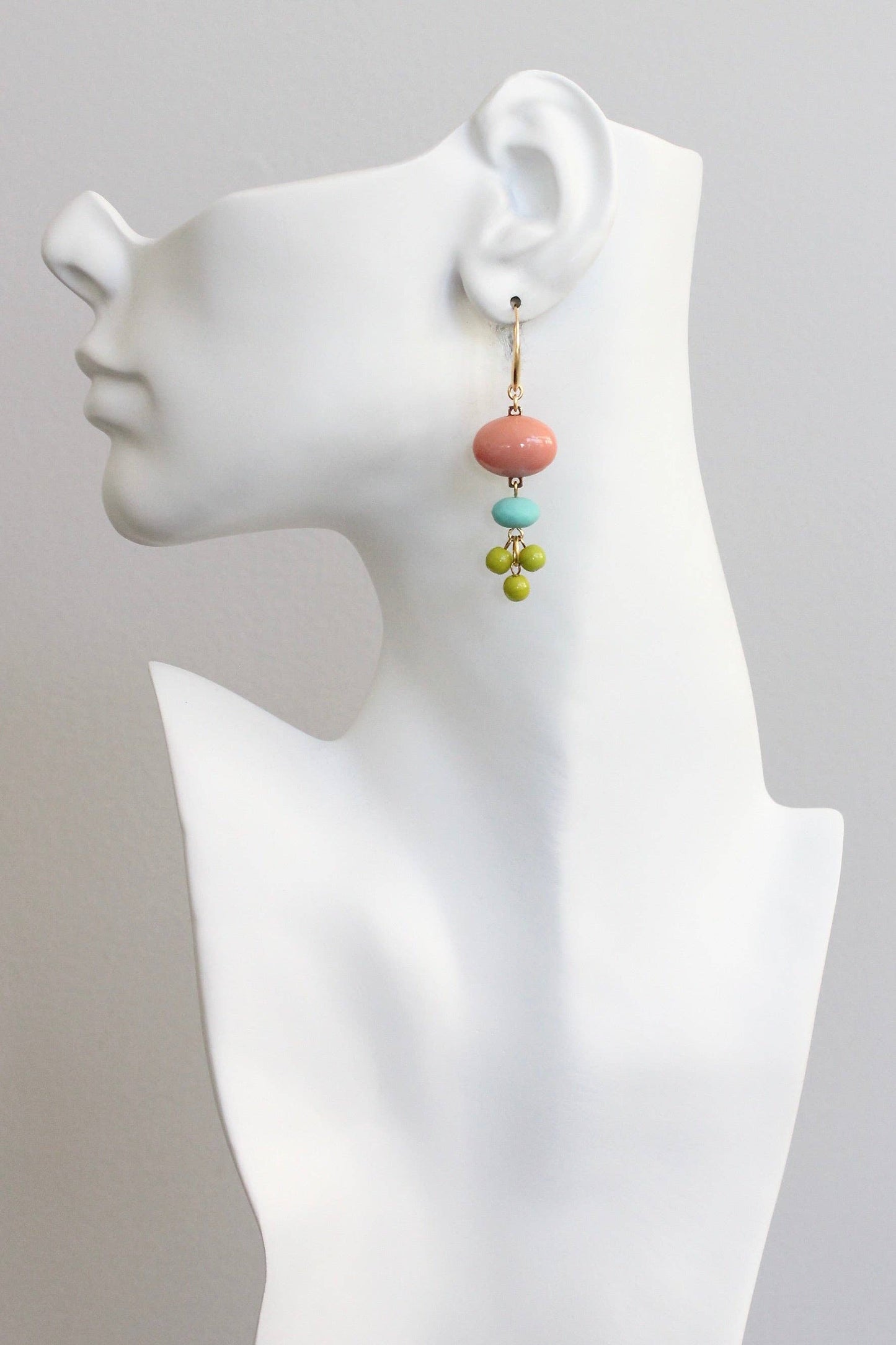 Colorful beaded earrings on a white mannequin bust against a gray background