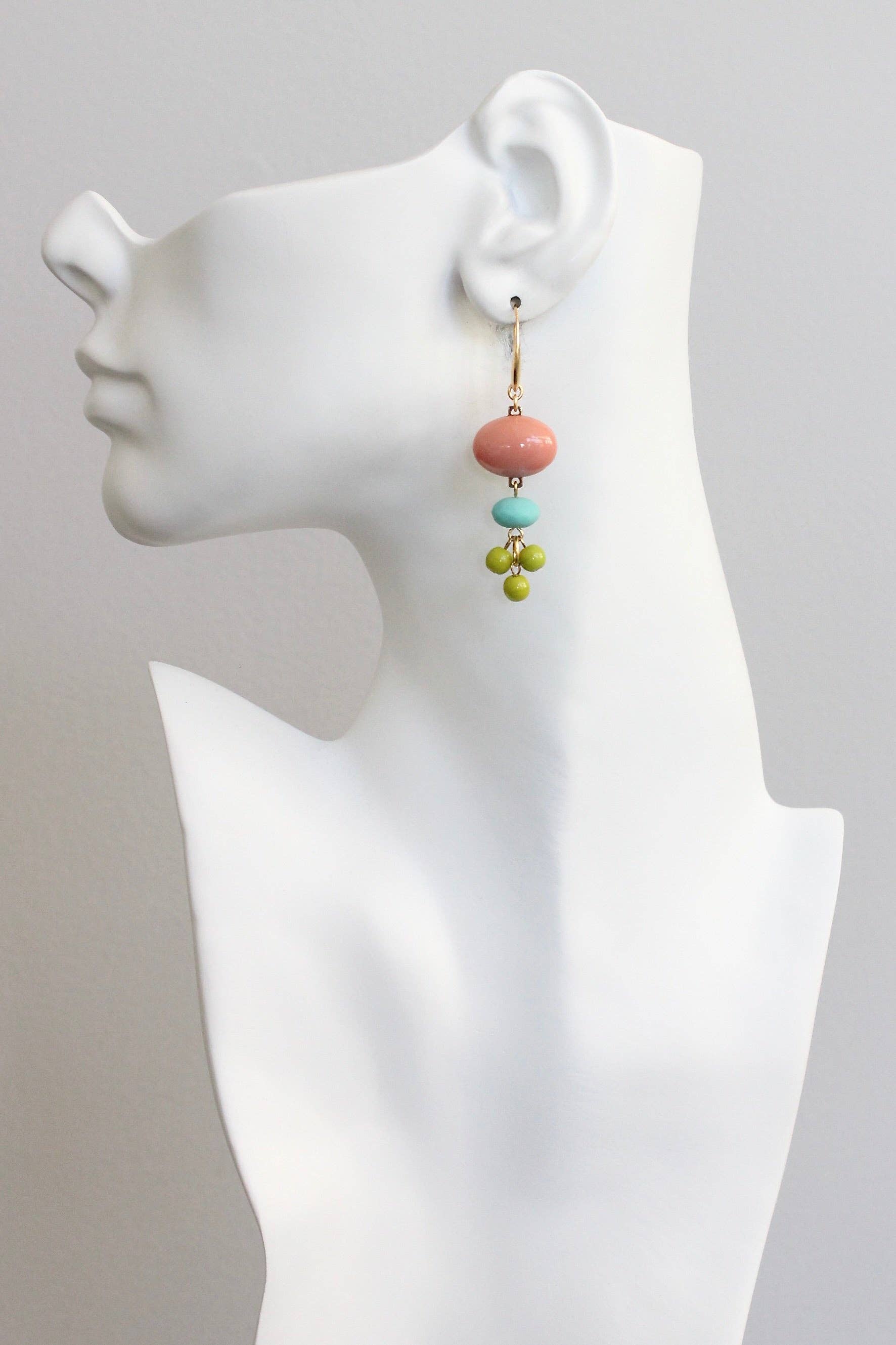 Colorful beaded earrings on a white mannequin bust against a gray background