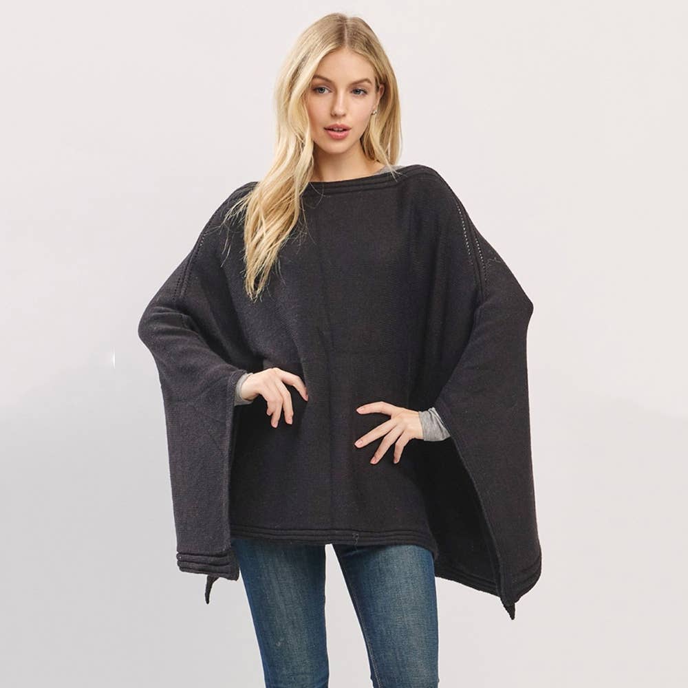 Woman wearing a black poncho over a gray sweater on a white background