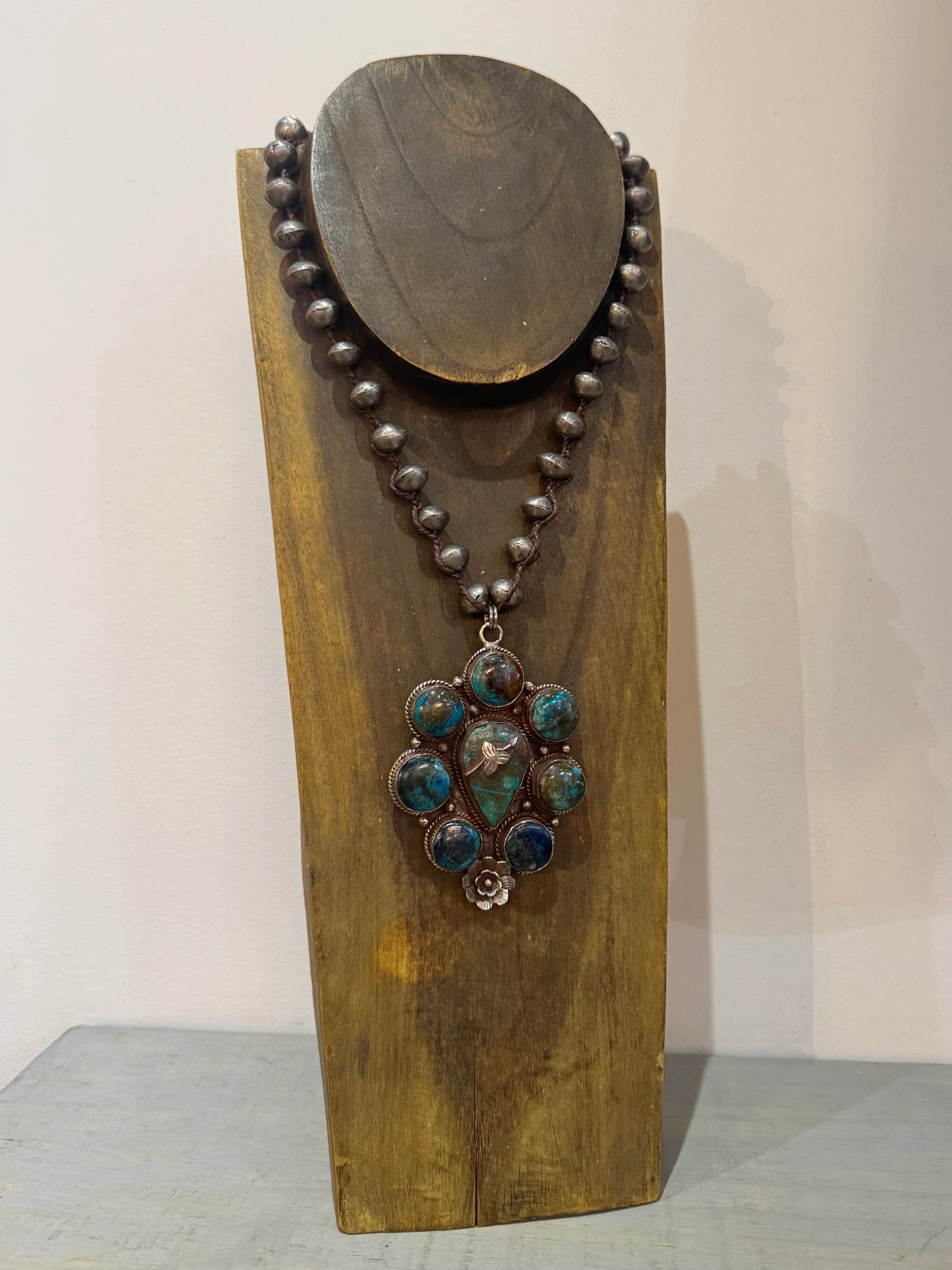 Necklace with a large pendant on a wooden stand against a white background