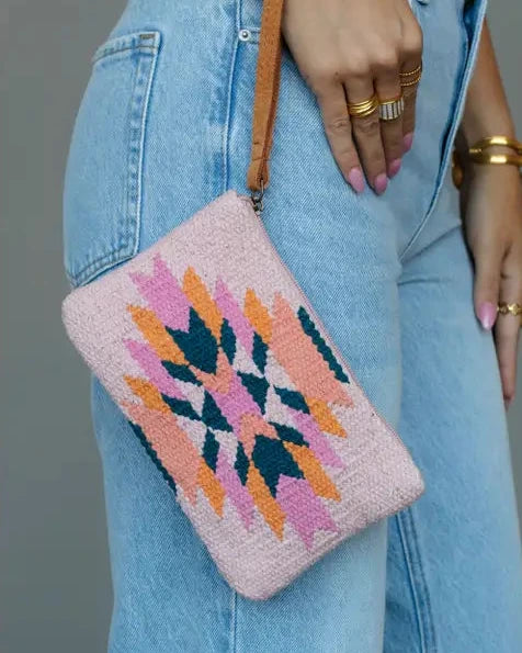 close up of woman in jeans holding pink and orange aztec pattern bag