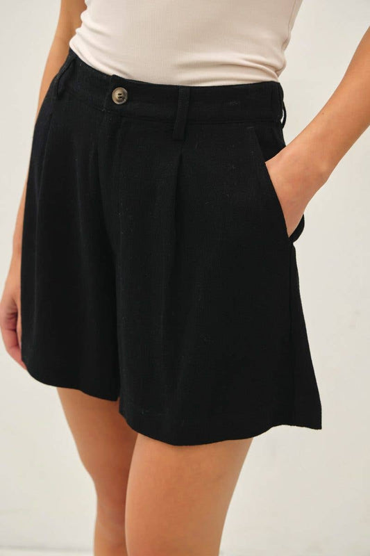 Black shorts worn by a person on a plain background