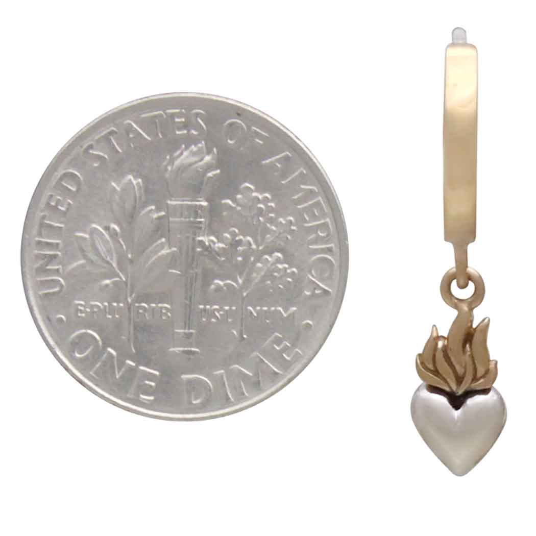 Small silver heart-shaped pendant with a flame design next to a U.S. dime on a white background