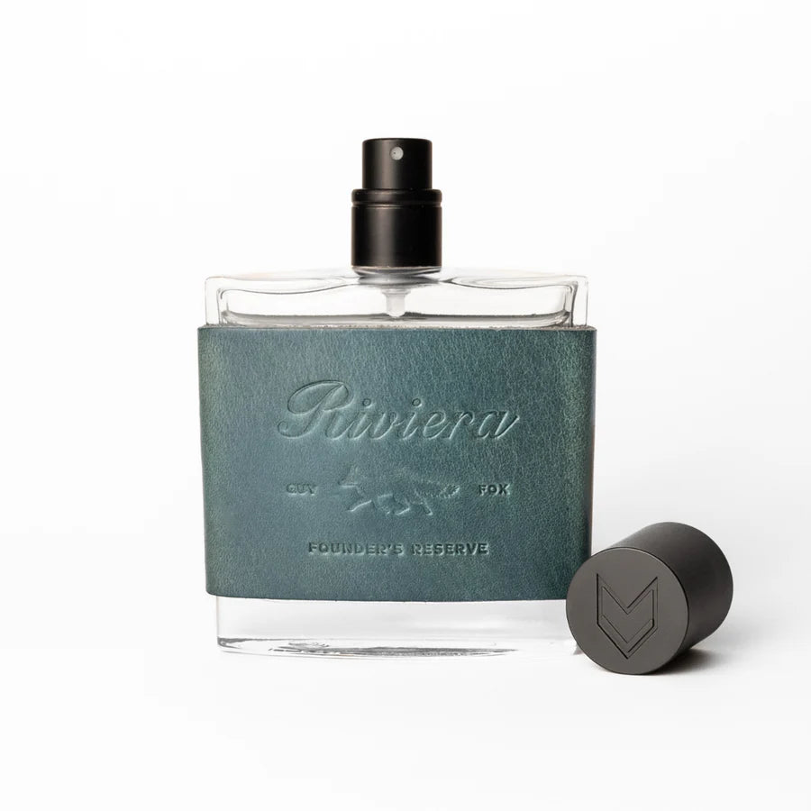 Perfume bottle with green leather cap and black spray nozzle on a white background