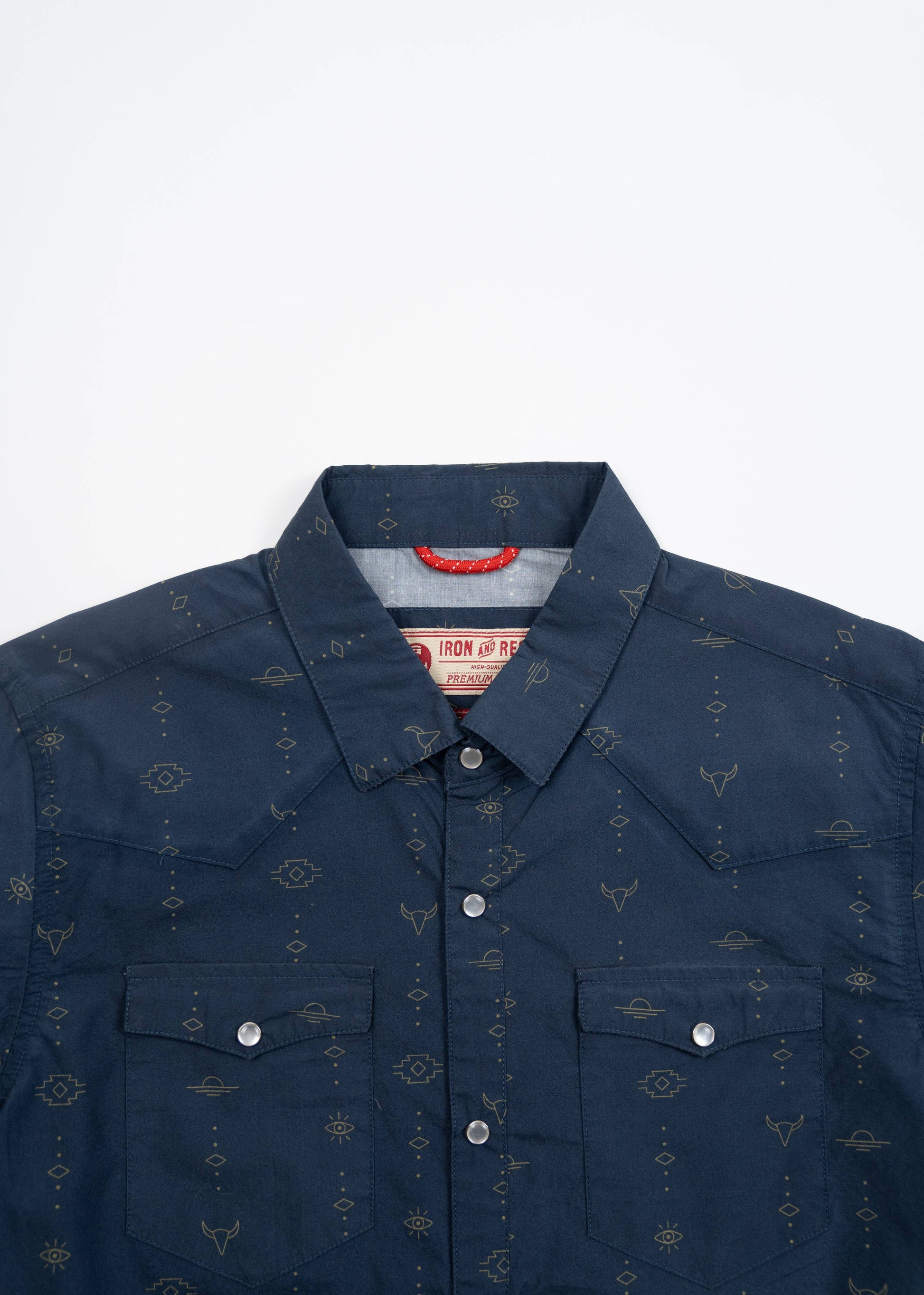 close up of locker loop draw cord on inside collar of navy western shirt with small patterns, double chest pocket and top entry button closure and pearl snap buttons.