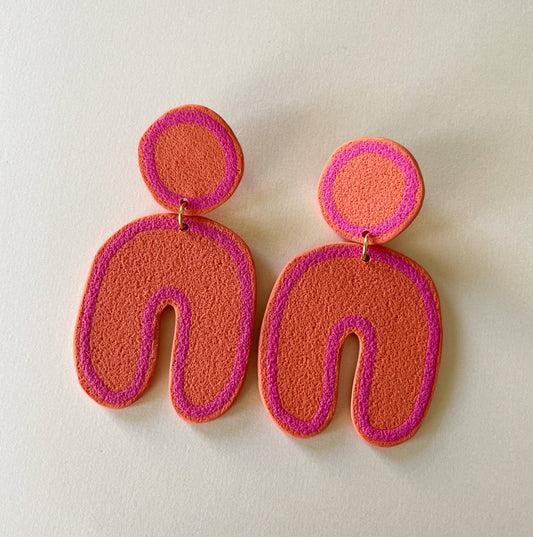 Clay post earrings in pink and orange in circle and u-shape. on a white background