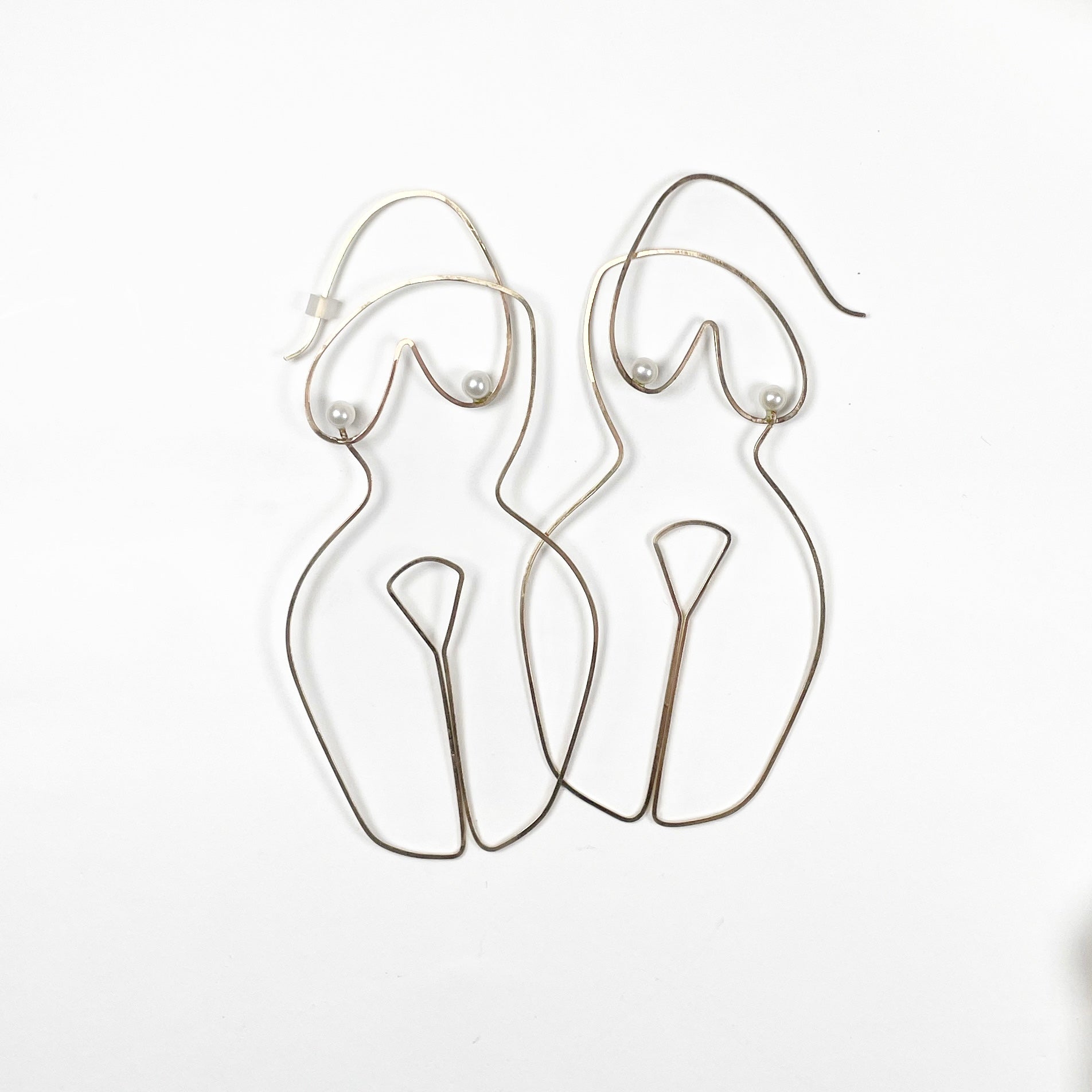 wire earrings shaped in the form of a woman's body with pearl accents as nipples