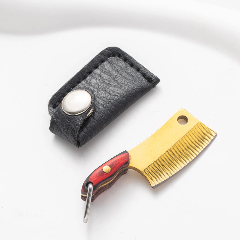 A mini butcher knife with a wood handle and gold blade, accompanied by a black leather sheath with a button closure.