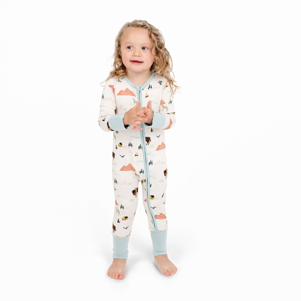 Child wearing a patterned onesie on a white background