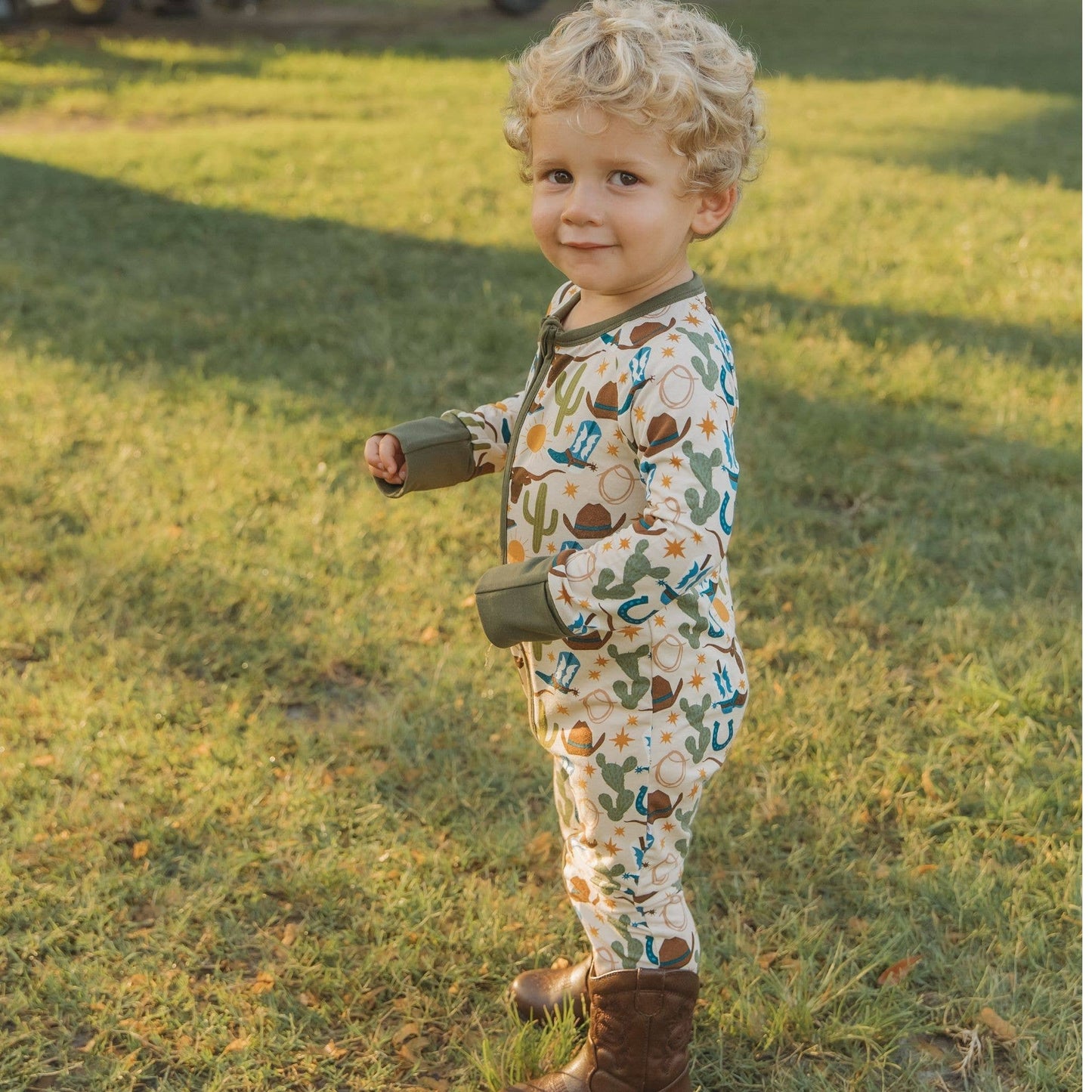 Child in a patterned outfit standing in a grassy field
