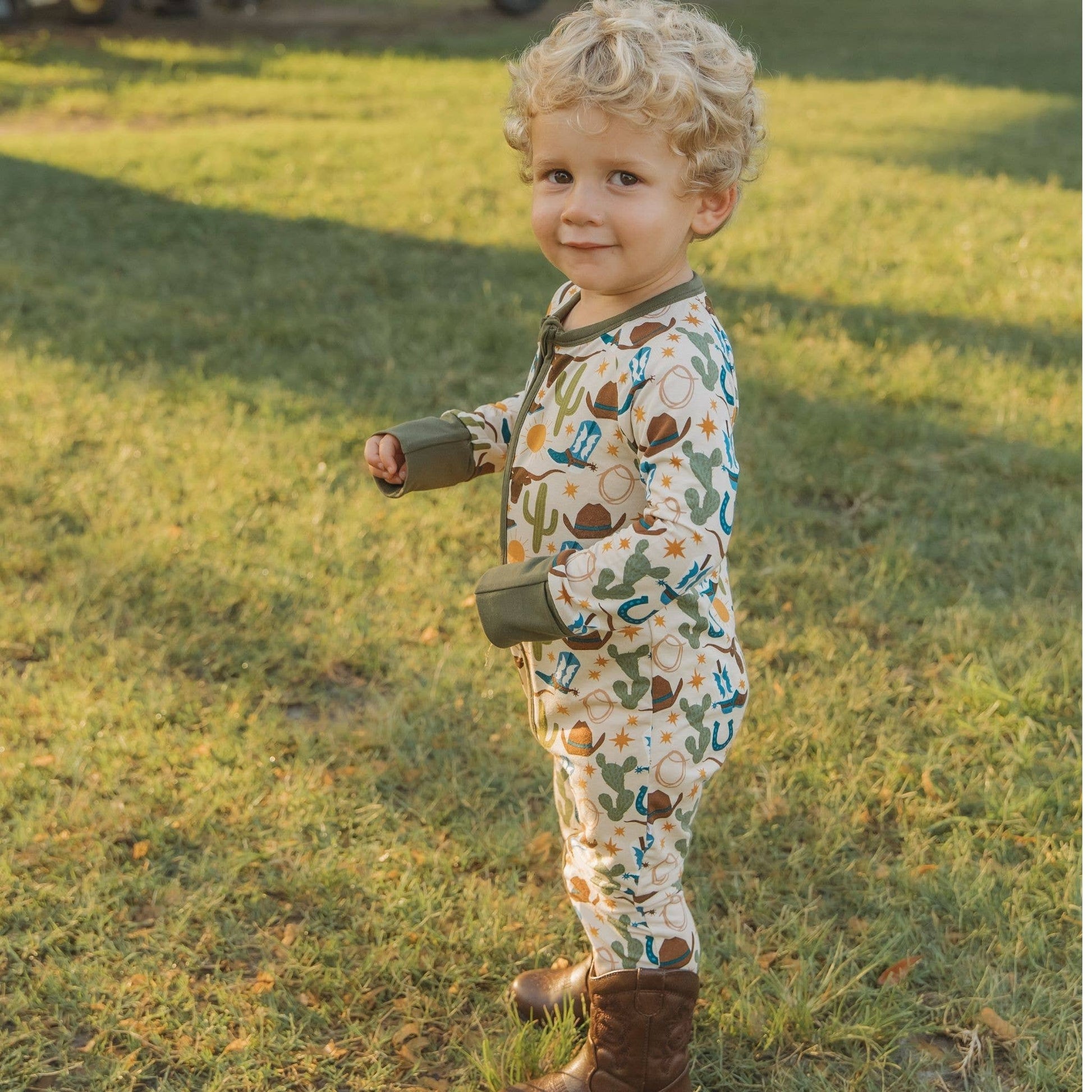 Child in a patterned outfit standing in a grassy field