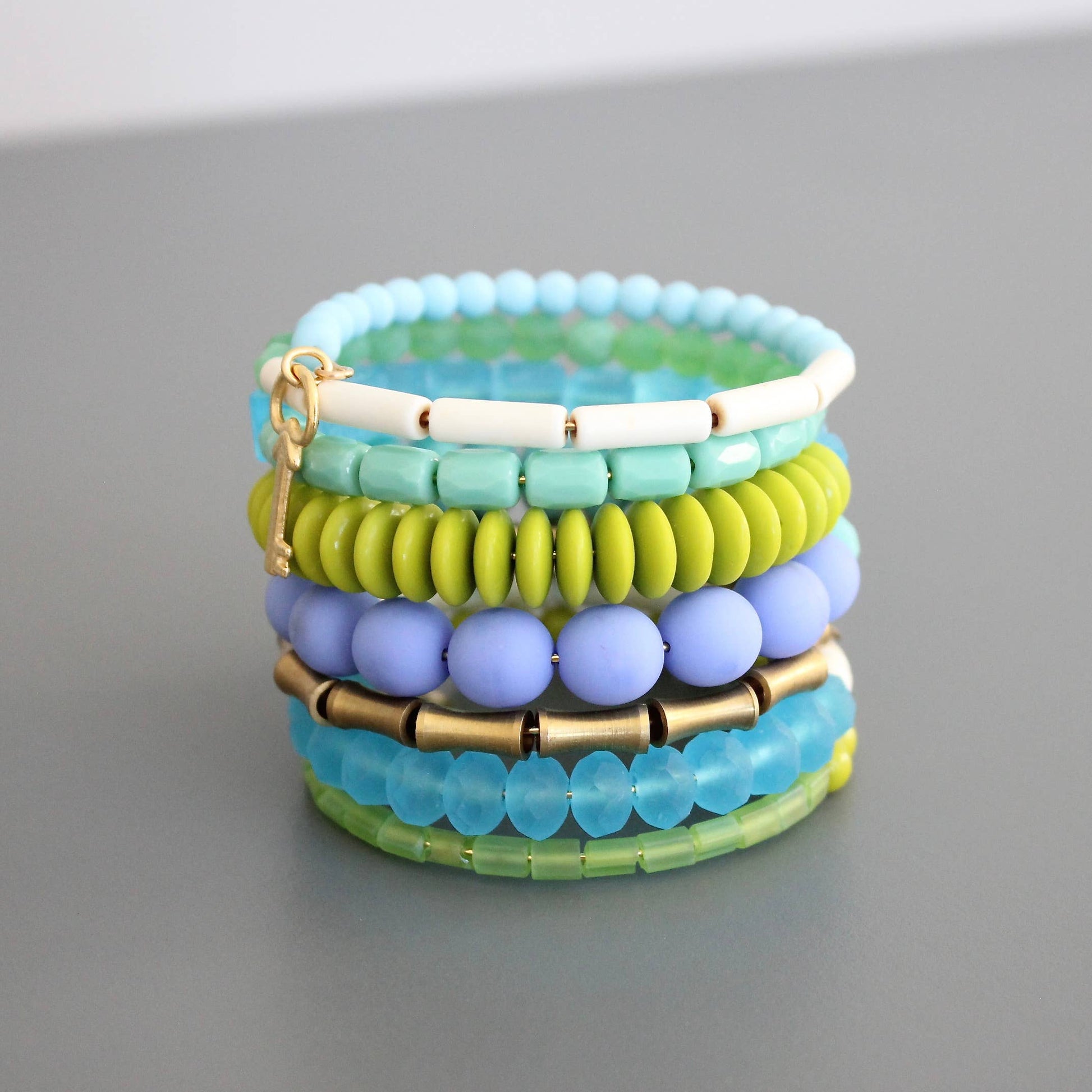 Stack of colorful beaded bracelets on a gray surface