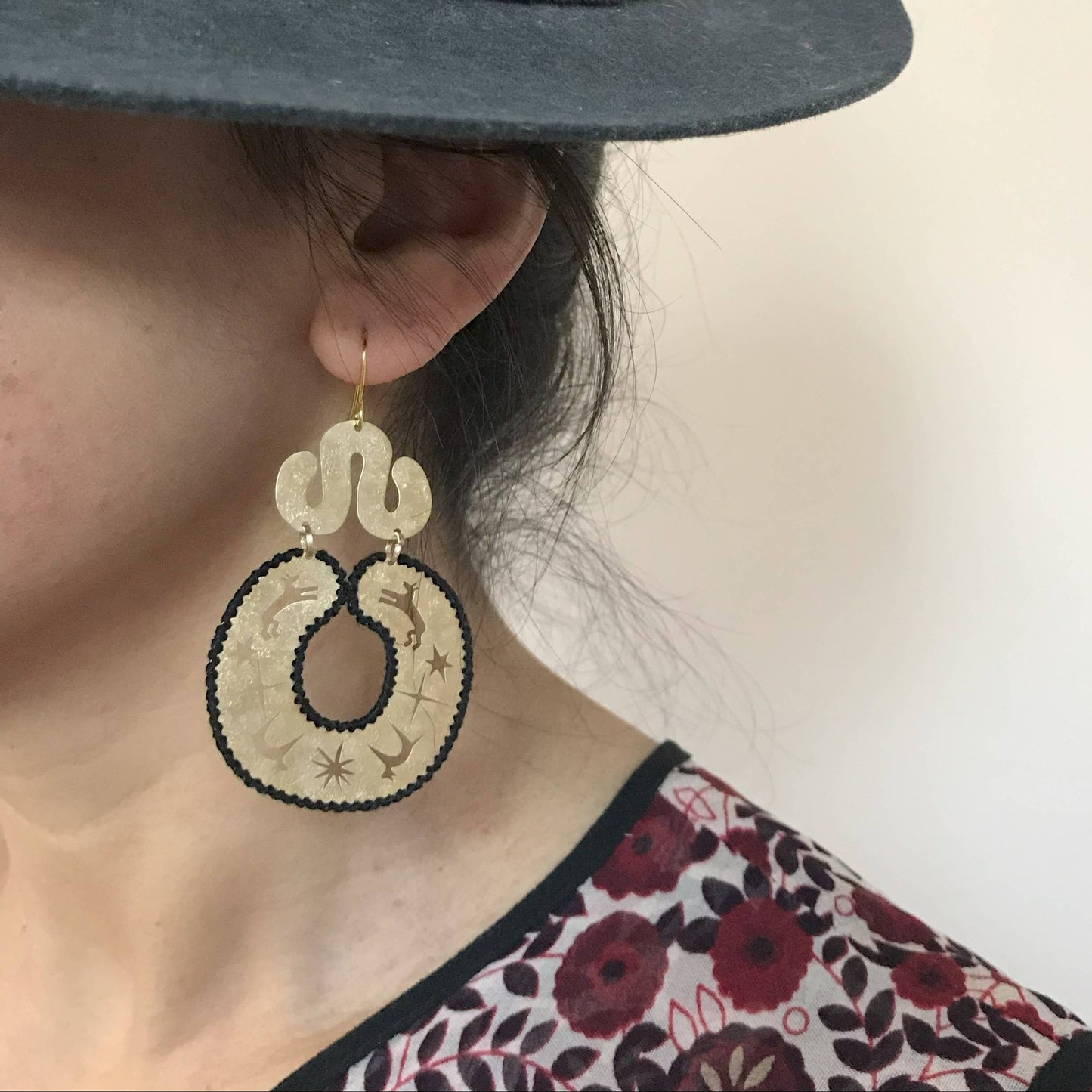 Close-up of a person wearing gold earrings with a neutral background