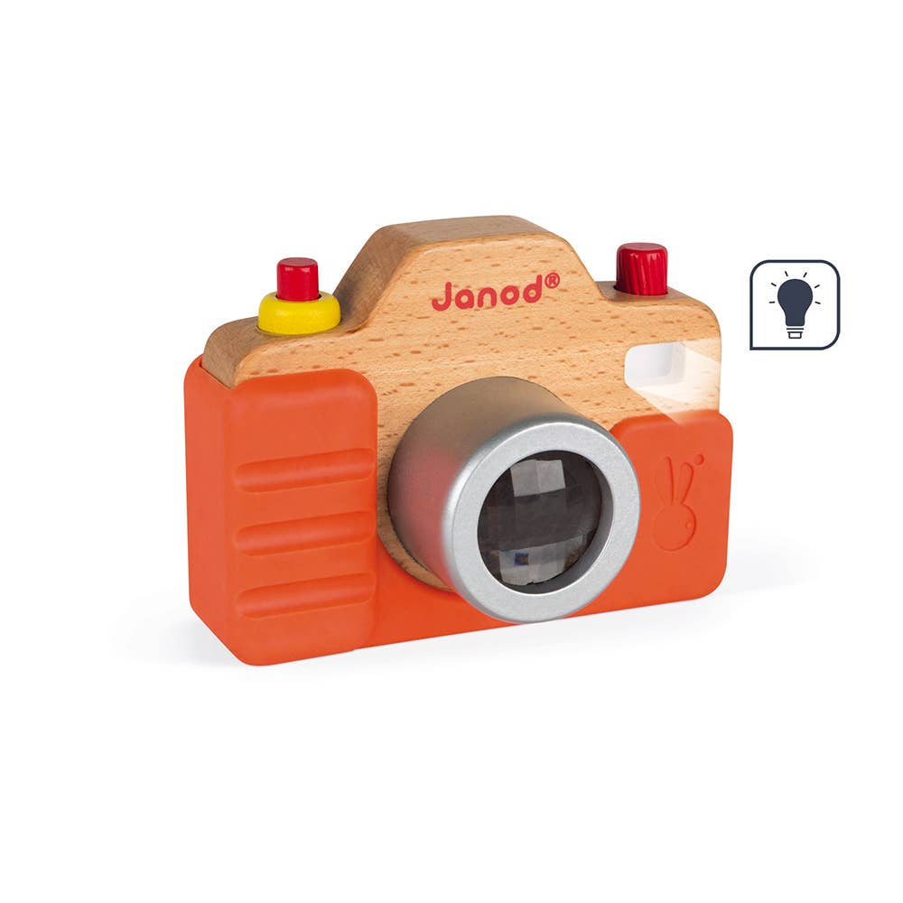 Wooden toy camera with orange body and red buttons on a white background, featuring the Janod brand.