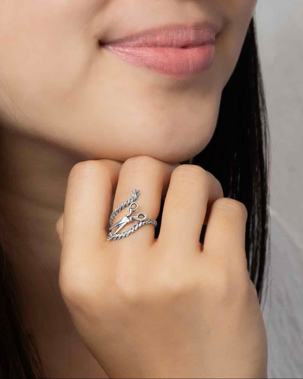 Woman wearing a silver ring with a detailed design on a neutral background