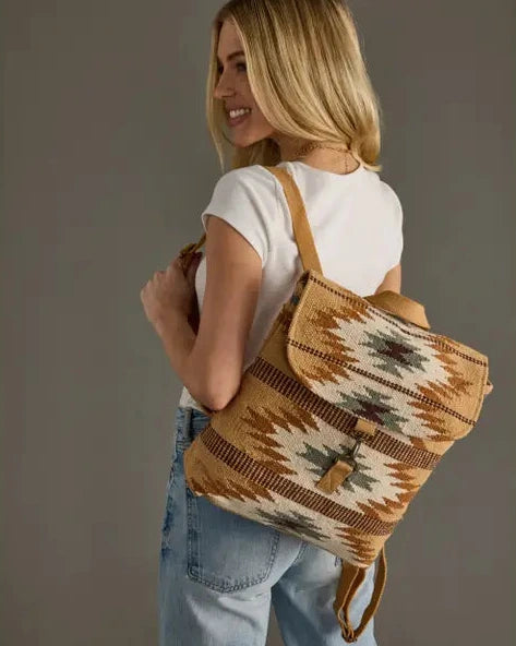 Woman holding a patterned backpack against a plain background