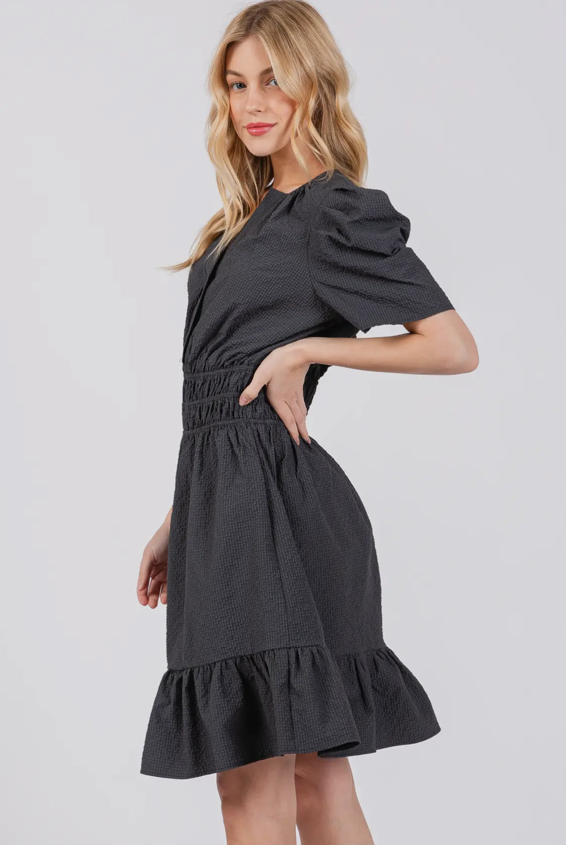 model showing side view of black puff sleeved ruffle dress