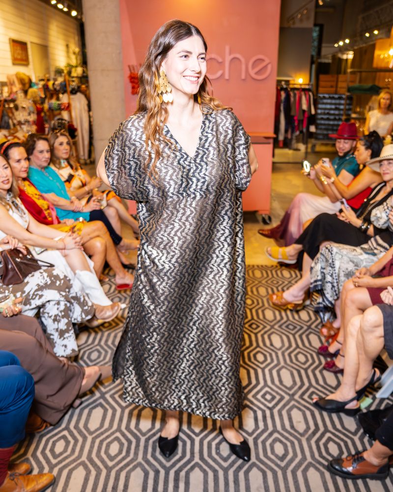 model wearing v-neck zig zag print long dress with statement earrings on a runway