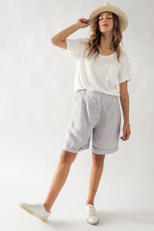 model wearing blue nautical stripe shorts, white shirt, sneakers and hat