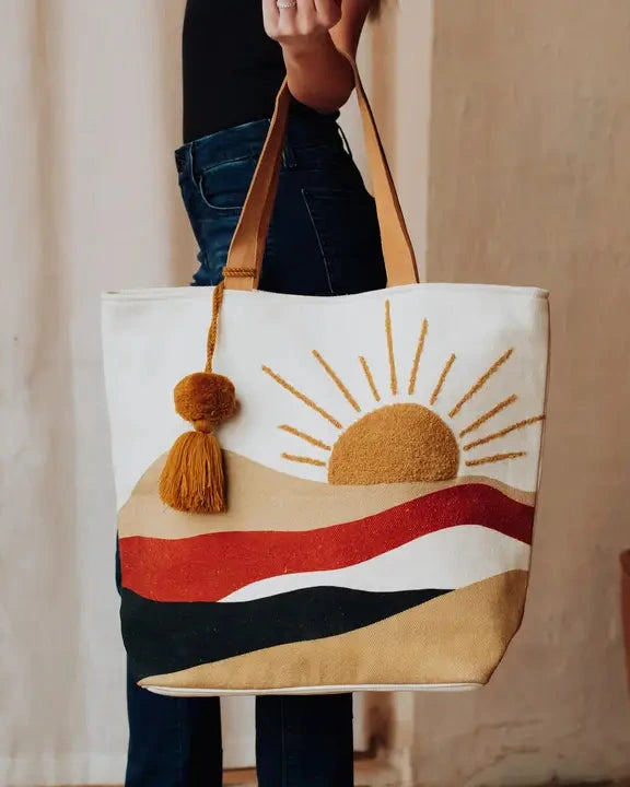 Tote bag with a sun design and tassels held by a person indoors.
