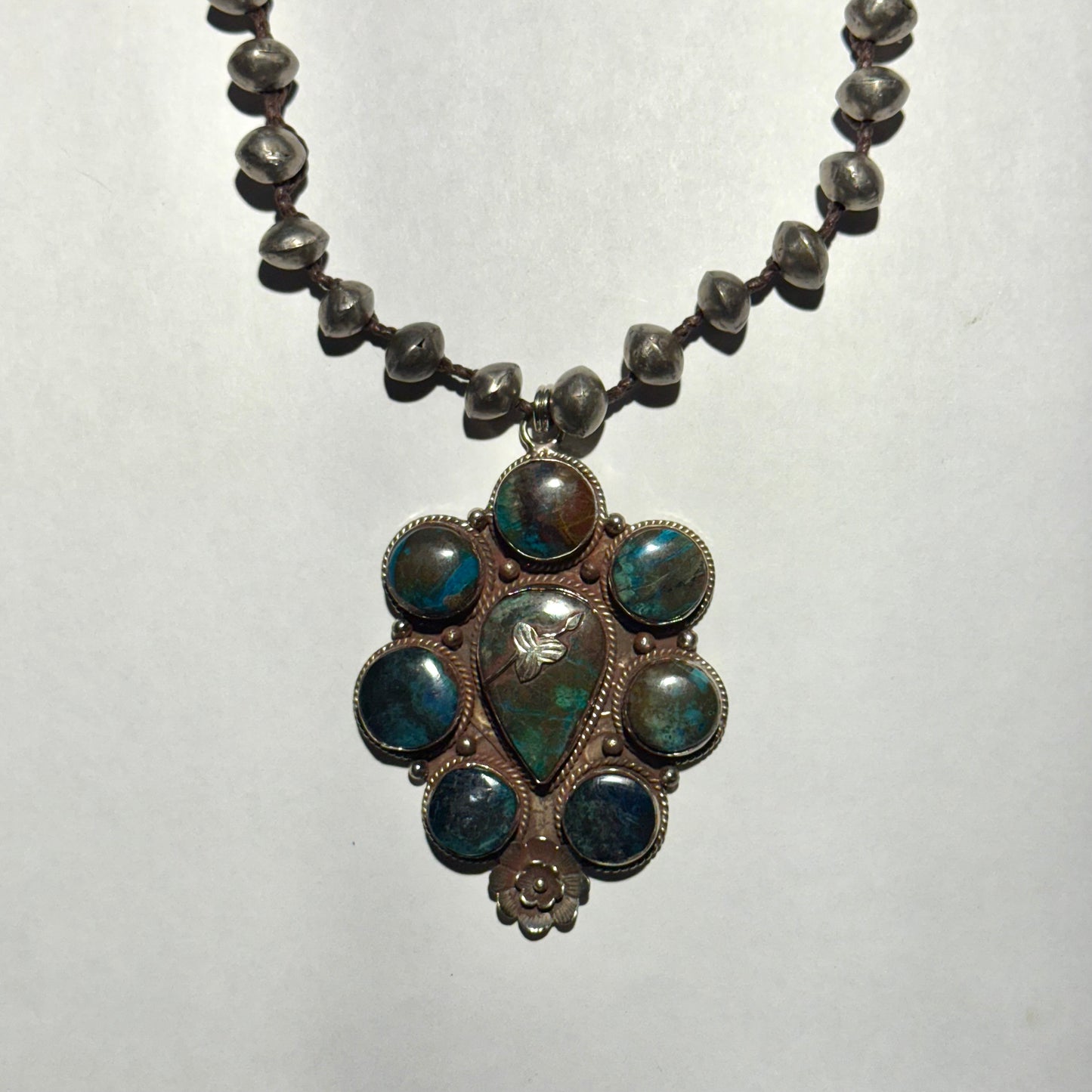 Necklace with a decorative pendant featuring blue stones on a white background