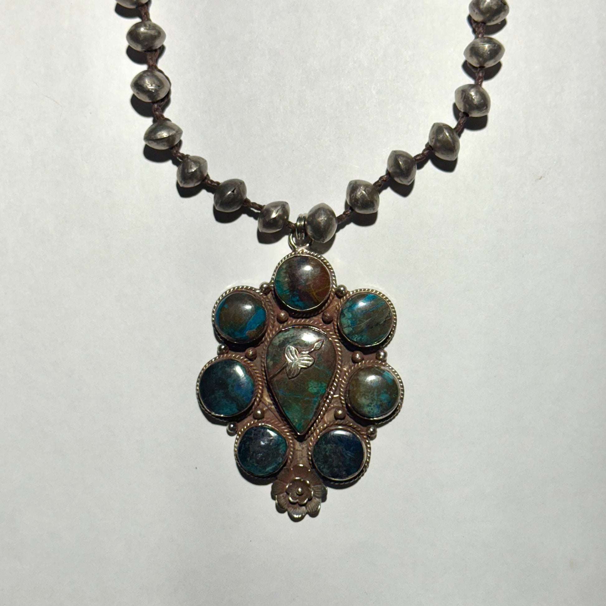Necklace with a decorative pendant featuring blue stones on a white background
